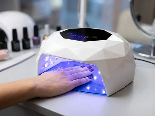 Hand härtet lila Gel-Nagellack unter einer weißen LED-Lampe aus – Heat Spike beim Gel-Aushärten