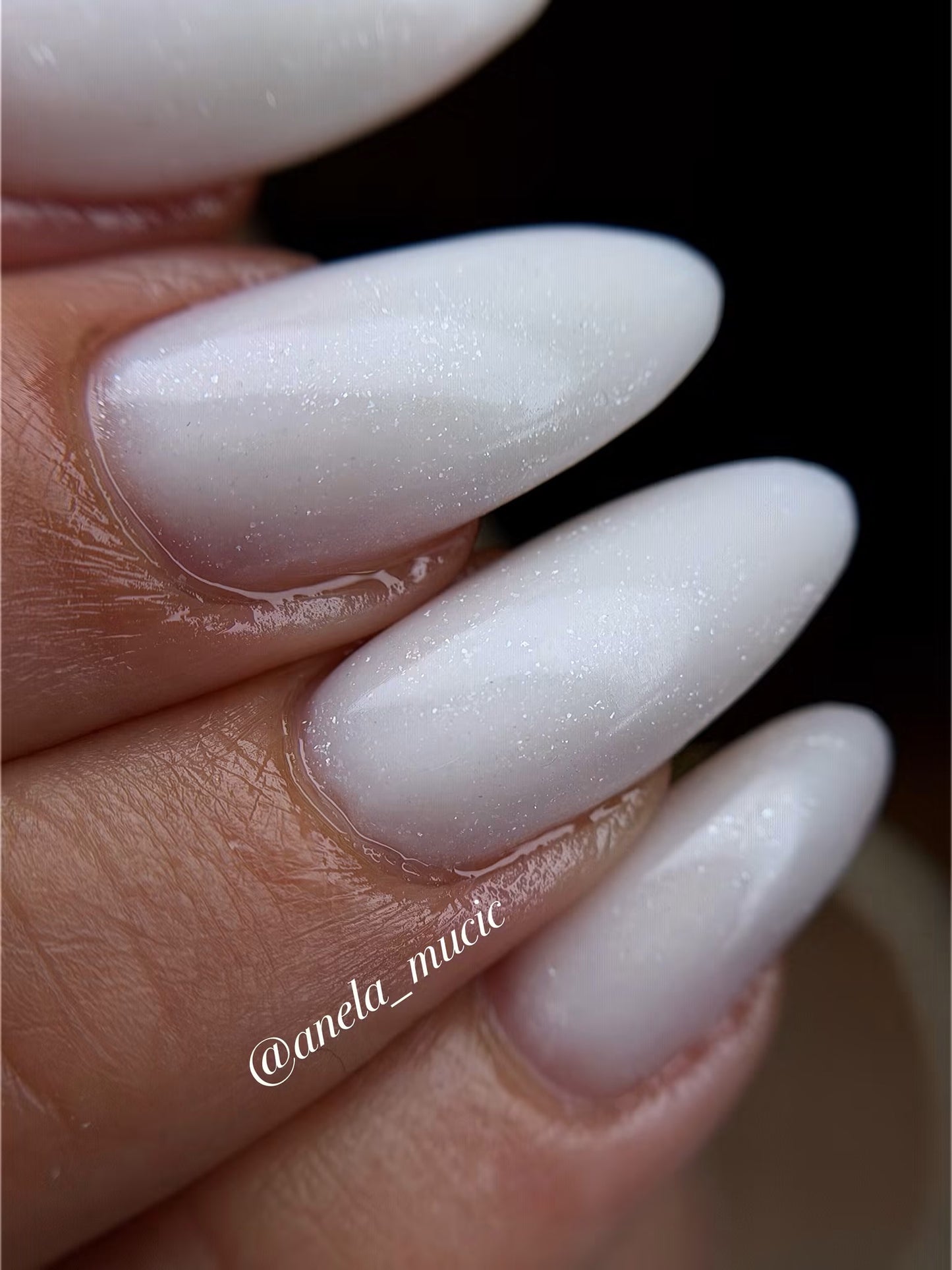 Milchig-weiße, glitzernde Nagelmodellage in Mandelform mit nahtlosem Übergang zum Naturnagel – Ergebnis eines gepflegten Refills bei Studio Amelie